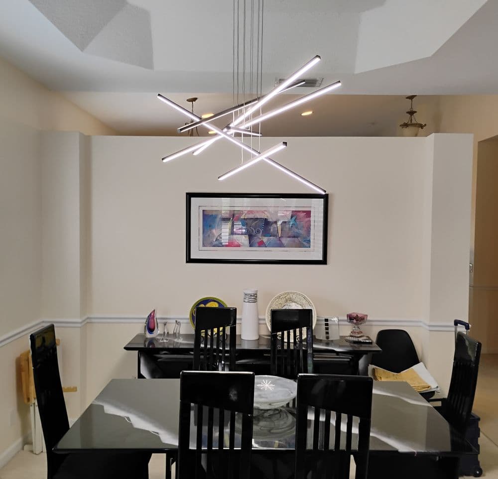 Modern dining room featuring a sleek black table, stylish chairs, and a contemporary light fixture.